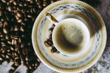Tasse de café expresso avec des grains de café sur un fond texturé gris