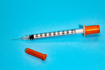 Fototapeta premium An insulin syringe for diabetes, on a blue background. Close-up of an empty syringe isolated. Plastic insulin syringe. Injectable medicine.