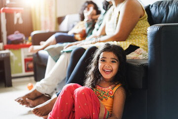 Indian family having fun at home sitting on sofa - Kid daughter having fun inside her house in living room - Focus on child face
