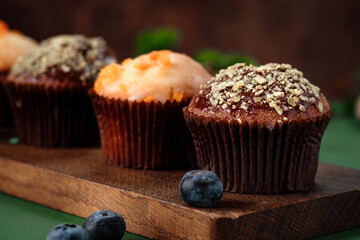 Chocolate and orange cupcakes on a wooden board. Sweet muffins on the table, close up