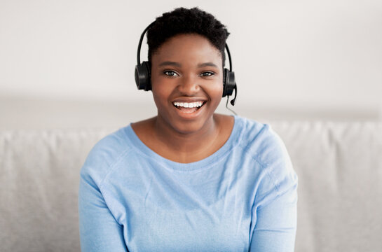 Black woman sitting, looking to camera wearing headset