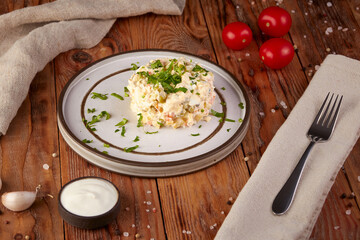 Russian traditional salad Olivier with meat and vegetables on a wooden background