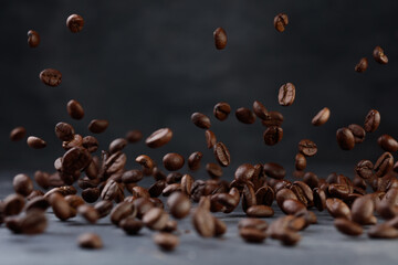 Levitation coffee beans. Grains of roasted coffee falling on gray stone background. Shallow depth of field	