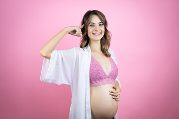 Young beautiful brunette woman pregnant expecting baby over isolated pink background smiling and thinking with her fingers on her head that she has an idea.