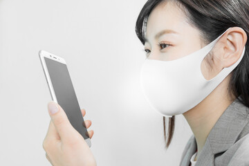 Woman wearing a mask uses a smartphone at work