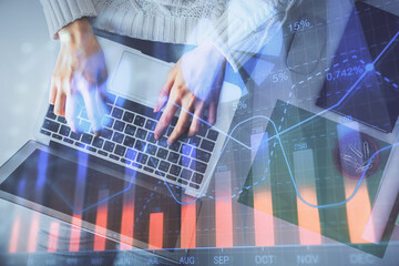 Multi exposure of woman hands working on computer and forex chart hologram drawing. Top View....