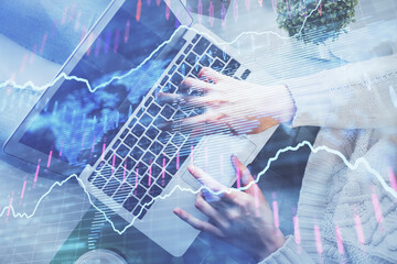 Double exposure of woman hands working on computer and forex chart hologram drawing. Top View....
