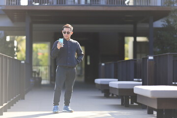 Fototapeta premium Asian man wearing training cloth for exercise is checking mobile phone for social media in the morning at residential house with copy space