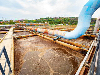 Pipe and walk bridge above waste water pool. Huge tank for residual rotting bacterias in sludge. 