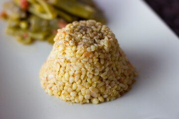 Bulgur pilaf with green beans in a white plate