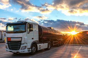 Tank truck with dangerous goods parked and the evening sun setting behind the mountains.