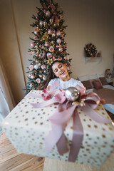 Fototapeta na wymiar Girl giving a gift on the background of a Christmas tree