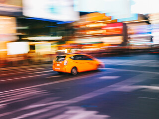 Blurred shot of a yellow taxi in motion through urban areas of a city at night