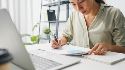 Freelance young Asia businesswoman casual wear using laptop working in living room at home. Working from home, remotely work, self isolation, social distancing, quarantine for corona virus prevention.