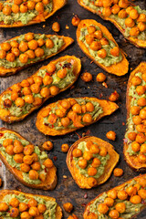 Sweet potato toast loaded with avocado guacamole and baked chickpeas on rustic metal oven-tray
