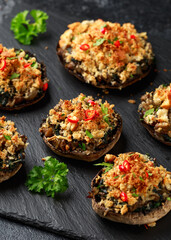 Stuffed mushrooms with spinach, bread crumbs and cheese on stone board