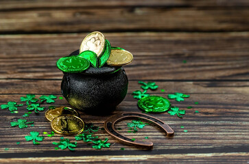 Background for St. Patrick's Day, March 17, with a lucky horseshoe, clover and a pot of gold on a...