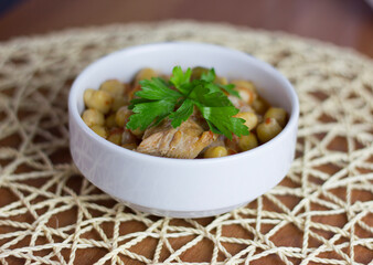 Chickpeas with meat in a white bowl with parsley