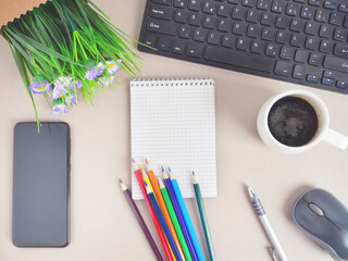 Office workplace with blank notepad, computer keyboard and writing utensils. Flat lay or top view of workplace with office supply and copy space