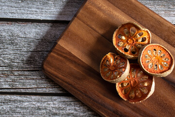 Dried quince fruit thinly on a wooden cutting board.