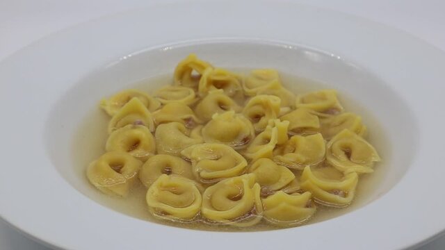 Tortellini in brodo (broth) isolated on white. Traditional italian pasta