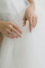 the bride's hands with a ring on her finger are holding the wedding dress