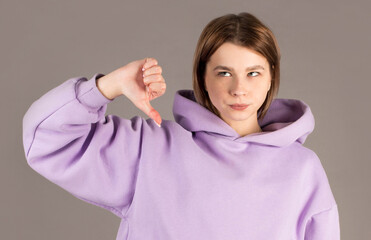 Woman showing thumbs down isolated on gray background