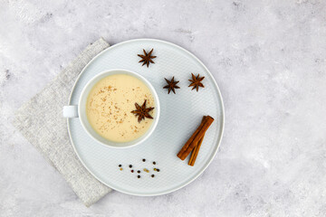 A cup of masala tea. Traditional Indian tea drink with milk and spices: cinnamon, anise, cardamom, nutmeg, pepper and ginger. Top view.