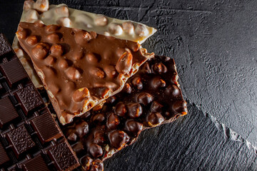 Three types of chocolate - black, milk and white on a black background with copy space