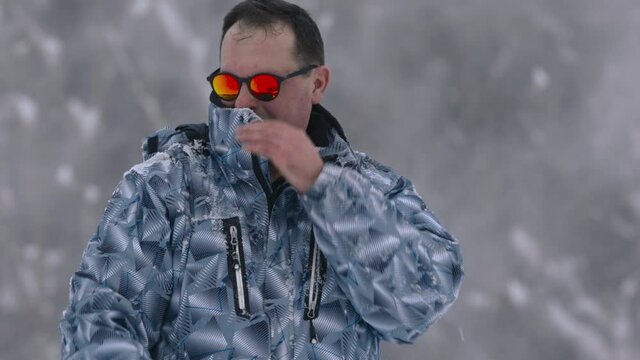 Man shakes off snow that has stuck to his jacket in snowy weather