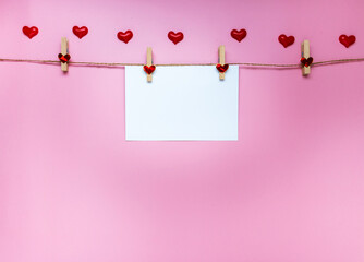 white greeting card and mini heart on pink background. for banner. The concept of Valentine Day. top view, copy space