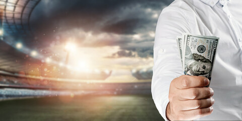 Close-up of a man's hand holding US dollars against the background of the stadium. The concept of...