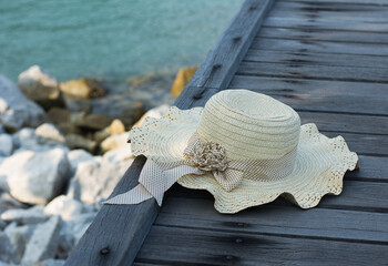 The hat is placed on a wooden bridge by the sea.