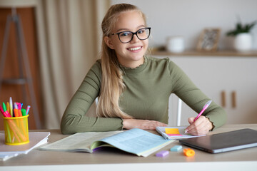 Fototapeta Cheerful teenager doing homework, making notes or writing essay obraz