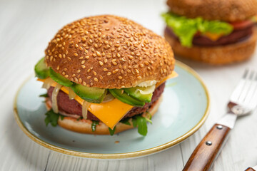 Fresh burger with vegan meat and vegetables, sprinkled with sesame seeds
