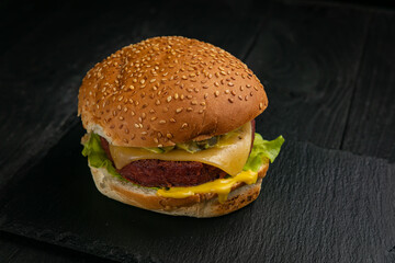 Fresh burger with vegan meat and vegetables, sprinkled with sesame seeds
