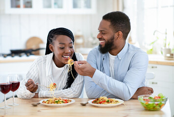 Beautiful african american couple having romantic lunch together in kitchen