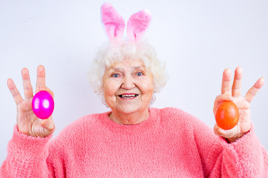 Happy 80 Years Old Woman Wearing Bunny Ears And Having Easter Eggs