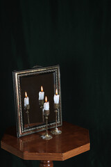 Mystic still life with mirror, reflection and two burning candles. Halloween concept