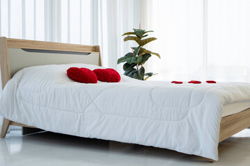 Red heart shaped pillow on bed in bedroom with white curtains, Valentine's day couple concept.