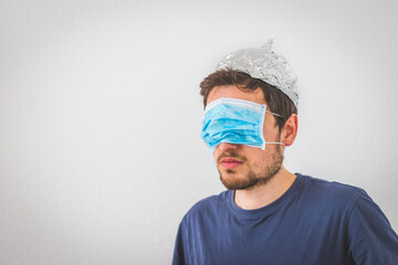 Conspiracy theory concept: Young angry man is wearing aluminum hat.