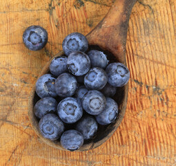 old wooden spoon with blueberries on a wooden table