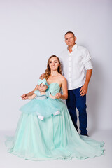 Fototapeta na wymiar beautiful young parents and one-year-old baby girl on awhite background