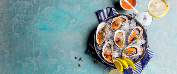 Oysters platter with lemon caviar and ice served on a Blue marine table.