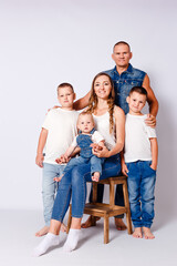 beautiful happy young family with three children in denim dress on white background