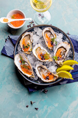 Oysters platter with lemon caviar and ice served on a Blue marine table.