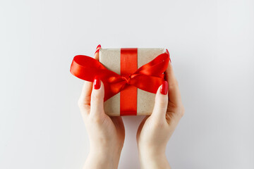 Gift with a red ribbon in hands on a white background