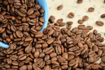 Coffee beans pouring out of a blue bowl Roasted Arabica grain coffee background