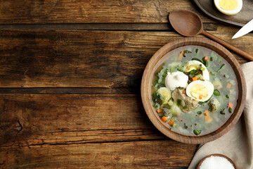 Delicious sorrel soup with meat and egg served on  wooden table, flat lay. Space for text