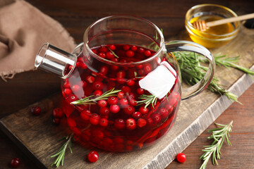 Tasty hot cranberry tea and fresh ingredients on wooden table